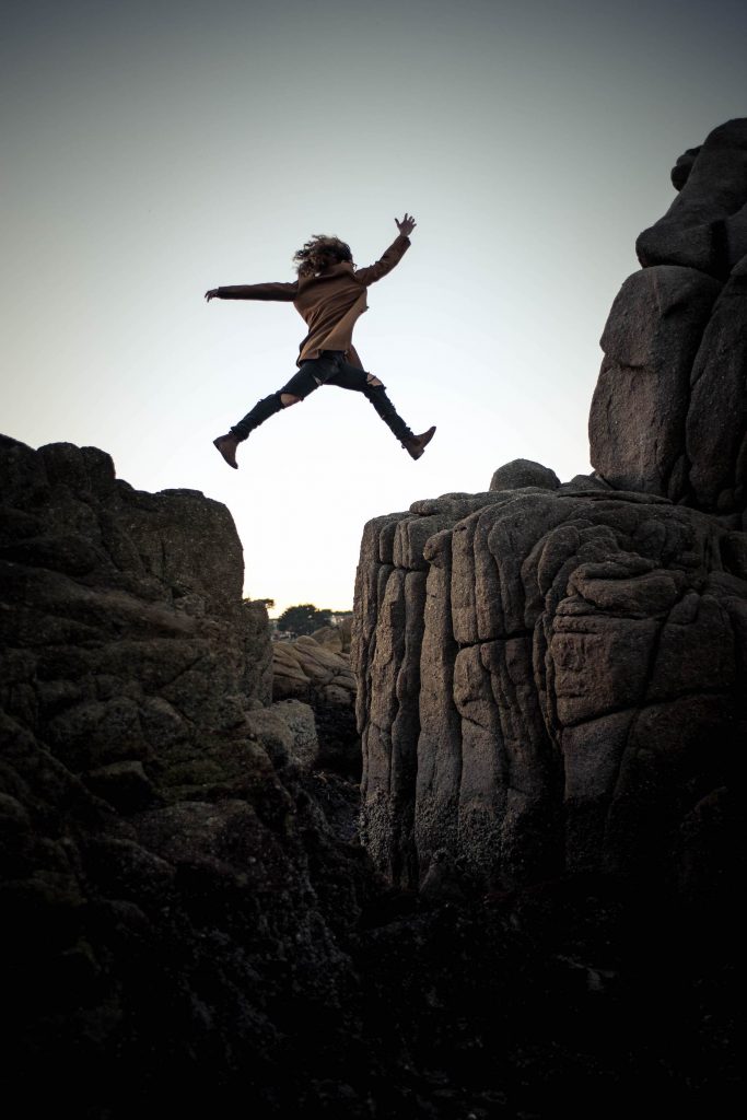Woman jumping from one rock ledge to another.