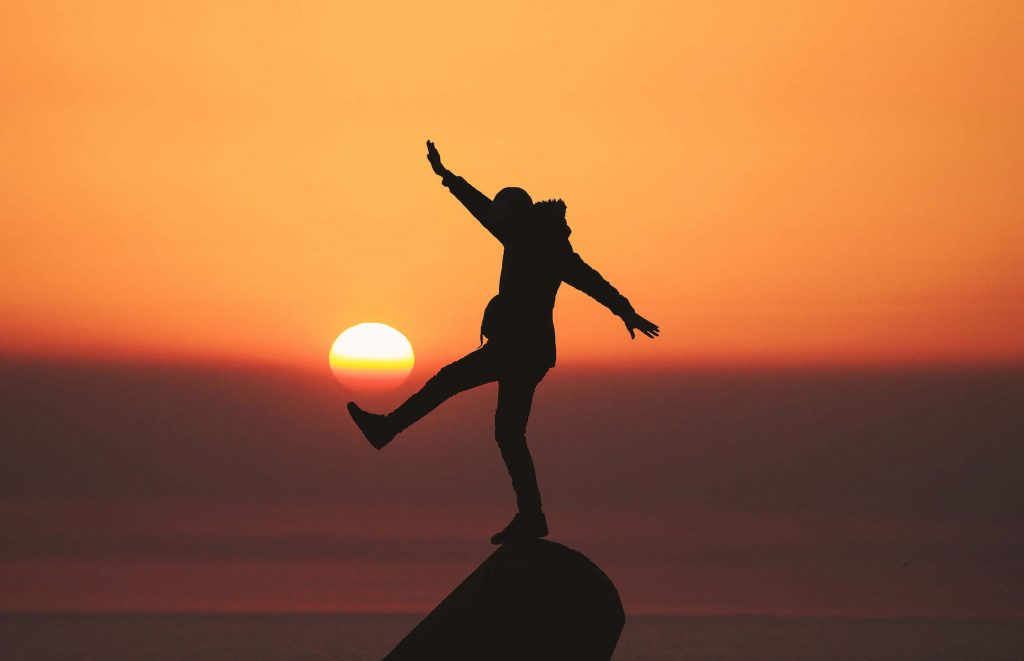 A silhouette of a person kicking what looks like the setting sun.