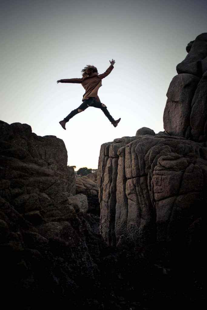 Woman leaping from one rock formation to another.